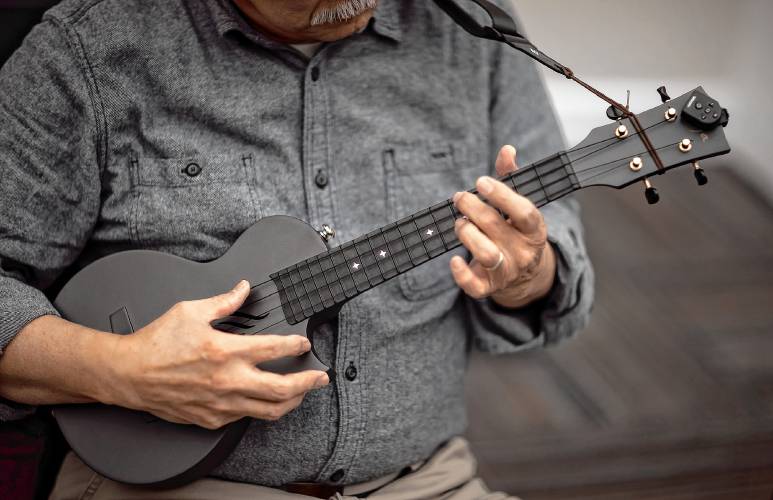 Kim Kimura of Hanover practices his ukelele before practice on Tuesday. Kimura is a member of several ukelele groups but likes this group, so he drives down from Hanover.