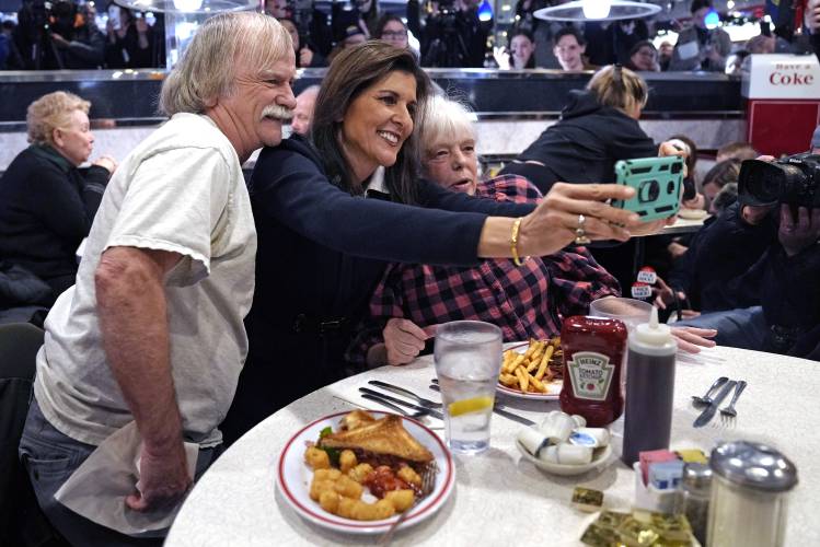 Republican presidential candidate former UN Ambassador Nikki Haley, center, poses for a selfie with guests during a campaign stop at Mary Ann's Diner, Friday, Jan. 19, 2024, in Amherst, N.H. (AP Photo/Charles Krupa) 