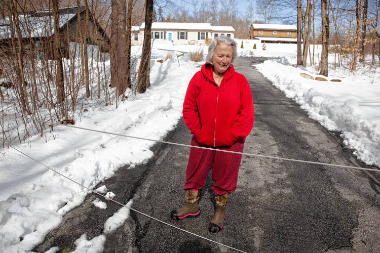 Brenda Payne stood behind the wires that blocked her driveway on East Penacook Road in Hopkinton on Monday. Payne was stuck in her home with her grandson since Saturday. She has a generator but was unable to get to work.