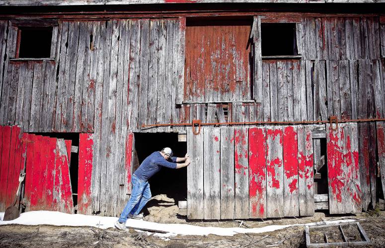 Cedar Mill Group project manager Nick Domenici moves a sliding door on the lower level of the red barn on Warner Road in Concord on Tuesday, April 9, 2024. The fact the barn had a solid roof that kept the rain out of the structure, the barn is solid shape.