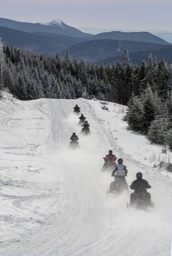 A line of snowmobilers make their way down Signal Mountain in Coos County, Errol.