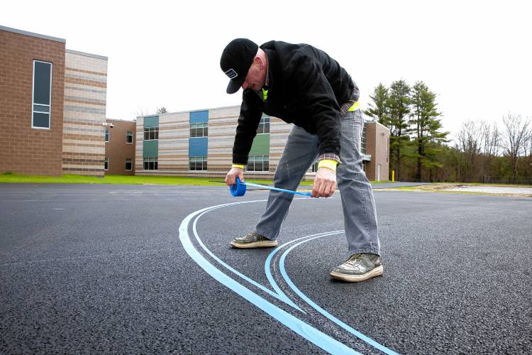 Mike Mattozzi of Tri-State Striping puts tape down for the lines for the basketball court at the Allenstown Community School on Thursday, April 18, 2024.