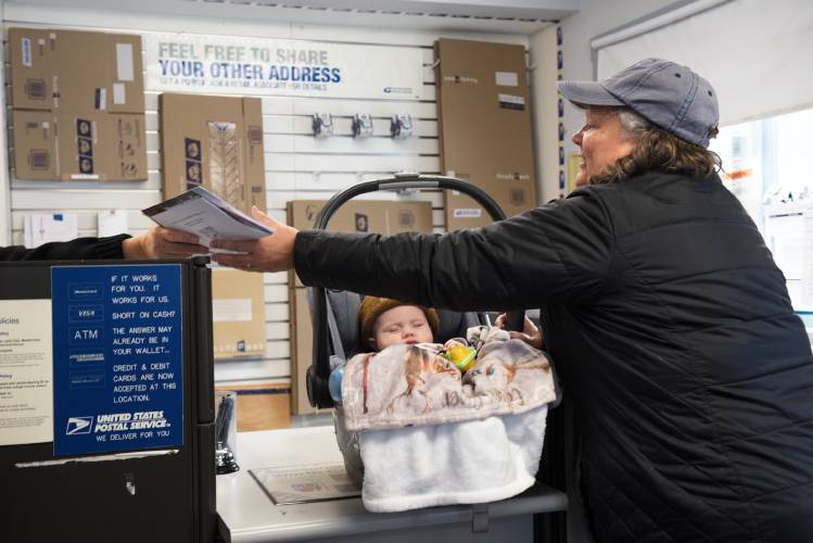 With postal delivery suspended across the town of Sharon, Carol Flint, of Newport, with her grandson Callum, picks up her mail in person from a clerk who declined to be identified on Friday. “It’s pretty sad it’s come to this,” said Flint, who said since the COVID-19 pandemic she’s seen a decline in public and community institutions. “Where’s the center of the community going to be?” she said.