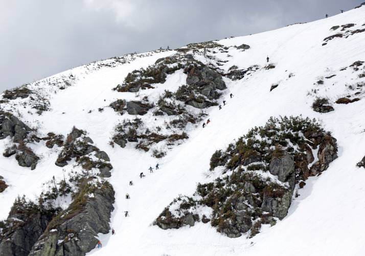 In this Sunday, May 3, 2015 photo, skiers and snowboarders climb up a steep slope that will take them to the top of Tuckerman Ravine, a glacial cirque that attracts thrill seeking skiers and riders on Mount Washington in New Hampshire. (AP Photo/Robert F. Bukaty)