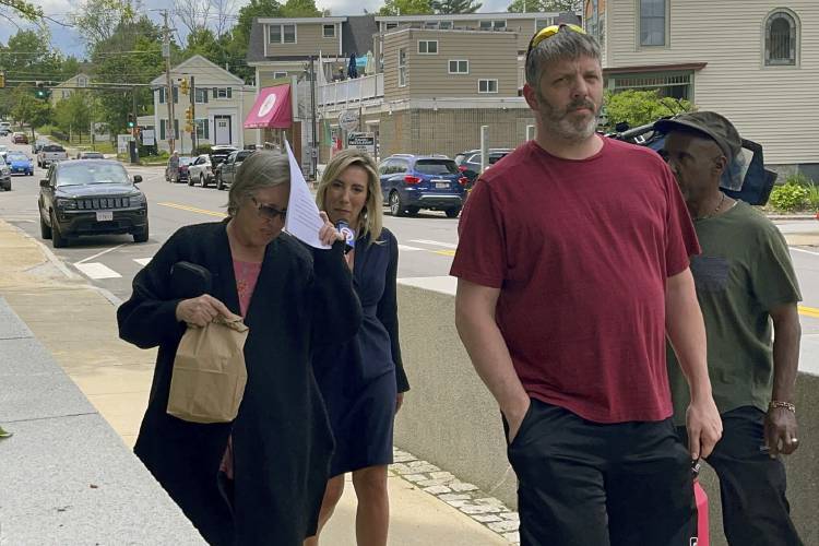 Denise Lodge, left, covers her face with a printout of the indictment against her as she walks from the federal courthouse last June in Concord. Lodge, 64, the wife of a former Harvard Medical School morgue manager has pleaded guilty to a federal charge after investigators said she shipped stolen human body parts to buyers.