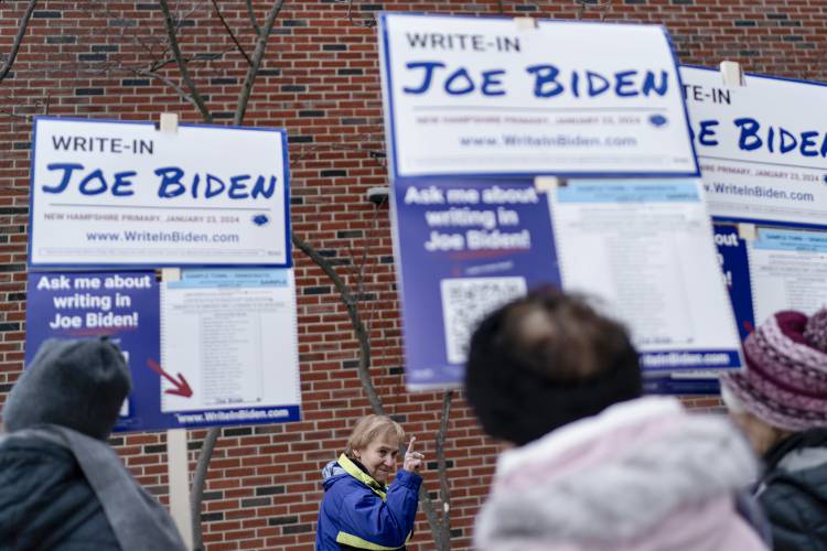 Janet Benard gestures toward supporters of President Joe Biden as she enters a polling site to cast a write-in ballot for the president in the New Hampshire presidential primary in Manchester, N.H., Tuesday, Jan. 23, 2024. (AP Photo/David Goldman)