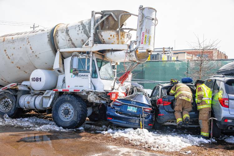 Concord firefighters break into the back of one of the vehicles that was hit by a Redimix cement truck on Monday, March 25, 2024. The parked car was empty and in the overflow lot of the Concord Bus Station off of Stickney Ave.