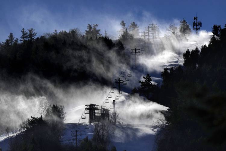 FILE - Snow is blown from snowmaking equipment near the summit of Pleasant Mountain ski resort, Dec. 21, 2023, in Bridgton, Maine. A new study says U.S. ski areas lost about 5 billion from 2000 to 2019 as a result of human-caused climate change. (AP Photo/Robert F. Bukaty, File)