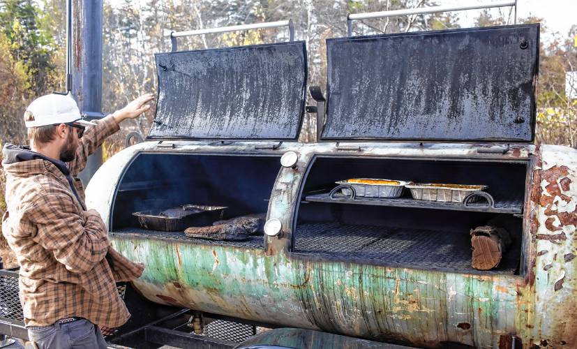 Concord native Ben Normandeau of 603 Bar-B-Q, a barbecue catering operation, checks the briskets and other baked item in his custom-made meat smoker outside of Lithermans Limited off of Hall Street in Concord on Thursday, November 1, 2023.