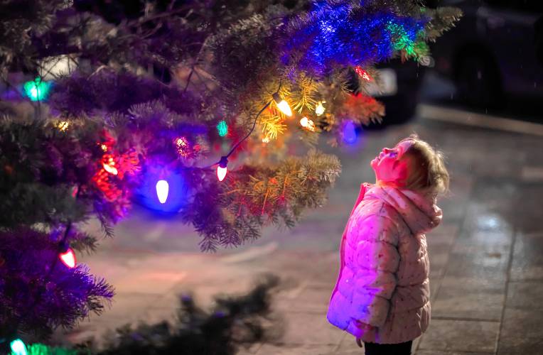 Lilith Benes, 4, looks up at the State House Christmas tree at Midnight Merriment in downtown  Concord on Dec. 1. The crowds still showed up in spite of the rain.