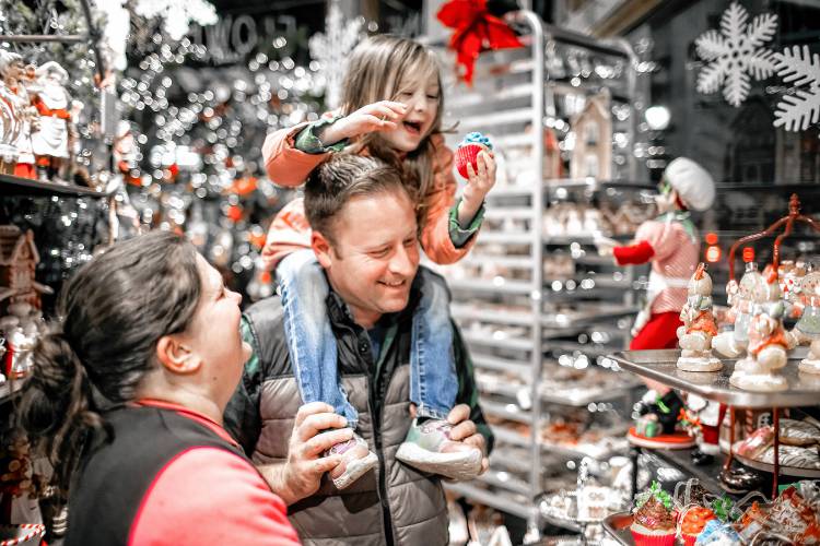 Andrea and Robert Doswell let their daughter, Aurora, 4, pick out a Christmas decoration at Cobblestones at Midnight Merriment in downtown Concord on Friday, December 1, 2023. The crowds still came out in spite of the rain.