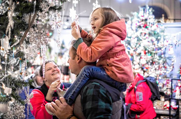 Andrea and Robert Doswell let their daughter, Aurora, 4, pick out a Christmas decoration at Cobblestones at Midnight Merriment in downtown Concord on Dec. 1. The crowds still came out in spite of the rain.