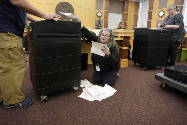 Lisa Hultgren, the Derry, N.H. town moderator, right, unloads ballots from a vote counting machine while testing the machines before the New Hampshire primary, at the Derry Municipal Center, Tuesday, Jan. 16, 2024. (AP Photo/Charles Krupa)