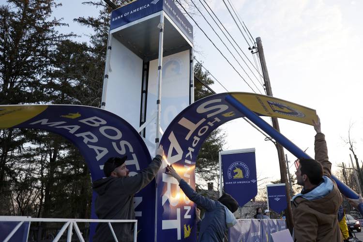 Workers affix banners at the starting line of the Boston Marathon, Monday, April 15, 2024, in Hopkinton, Mass. (AP Photo/Mary Schwalm)
