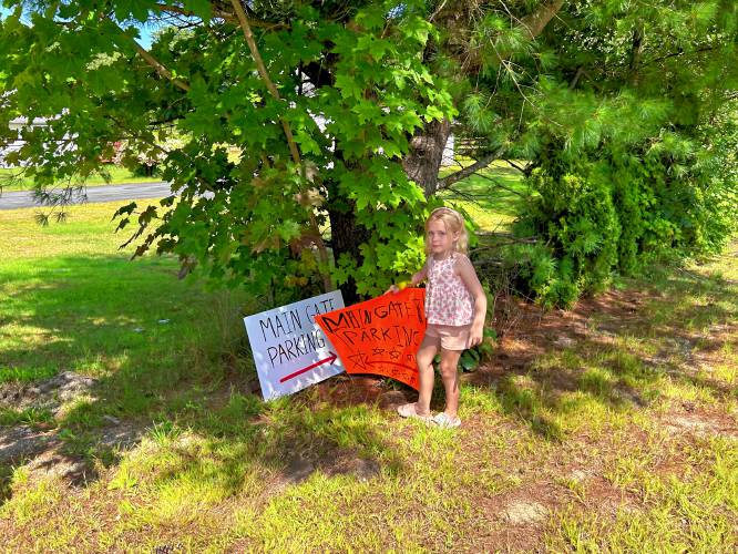 Jemma Dearborn, 7-year-old daughter of Justin Dearborn, stands at the front of the yard with the sign she made herself, ready for the temporary parking spaces at their home.