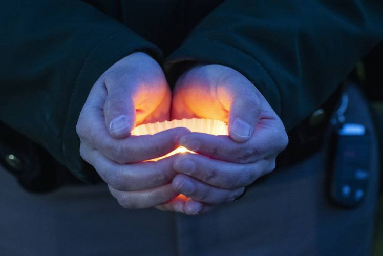 A New Hampshire State Trooper holds a candle during the vigil ceremony on Monday evening for former Franklin Police chief Bradley Haas who was killed at the New Hampshire State Hospital.