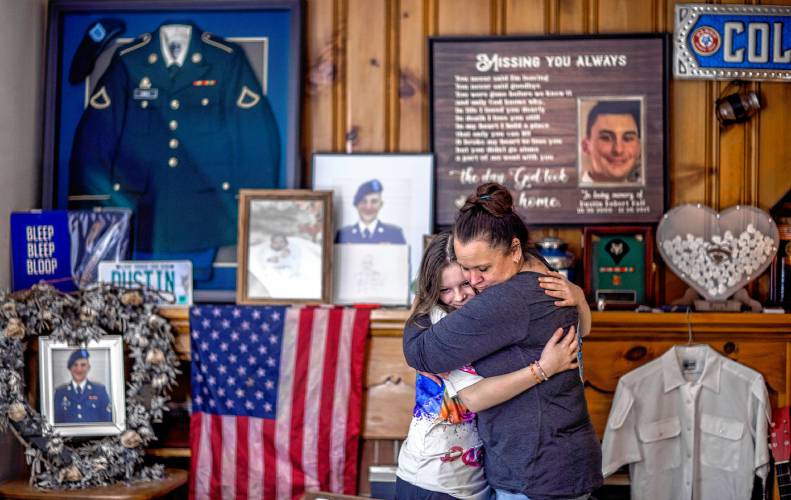 Heather Demello and her niece, Serenity, hold on to each other in the room that she has devoted to her son, Dustin. Soon she will include photos of her sister as well.