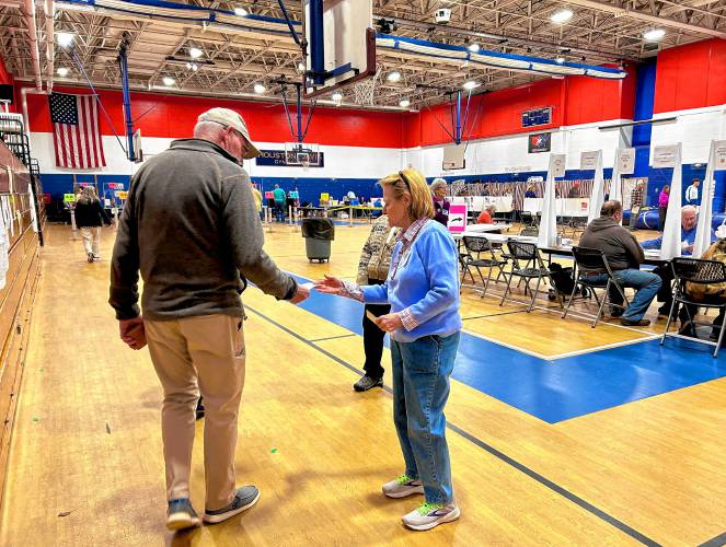 A poll worker at Broken Ground School in Ward 10 hands out voter guides to residents who came to cast their ballots.