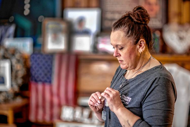 Heather Demello holds on to her son’s dog tags in the room she has devoted to him.