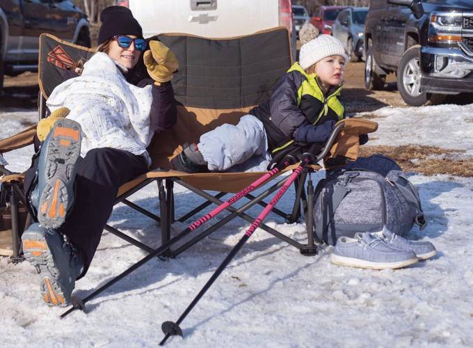 Rebecca Vallieres, left, watches her family on the slope, along with her 2-month-old daughter Robby Vallieres on her lap and 2-year old Emilie Hibbard at the Veterans Memorial Ski Area in Franklin on Sunday afternoon.