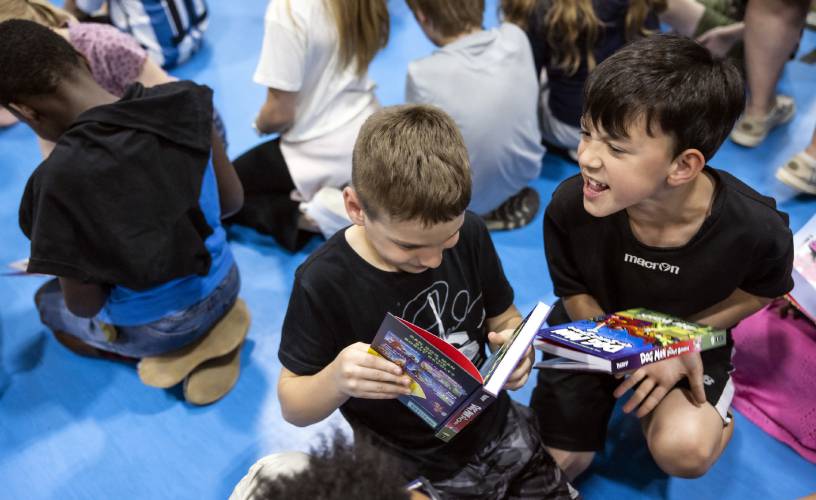 Third graders Vlad Milanovic (center) and Ashton Beauchesne (right) react as they get their Dav Pilkey’s latest book, Dog Man: the Scarlet Shedder at Beaver Meadow School on Monday, June 10, 2024.