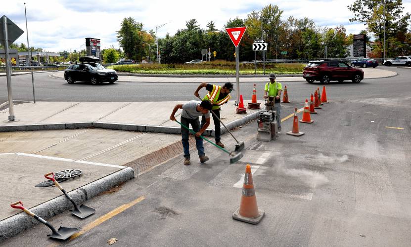 Workers from Merrill Construction clear off the old striping around the traffic circle in front of the new Market Basket near exit 17 on Tuesday, September 24, 2024. The crews was going to replace the fading striping around the circle.