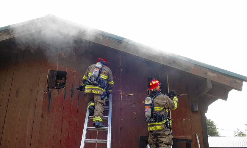 Firefighters vent the roof of the Carter Lodge at the Hidden Valley Scout Camp in Gilmanton on Monday, December 11, 2023. The smoky fire at the isolated camp went to two alarms and drew fire companies from around the area.