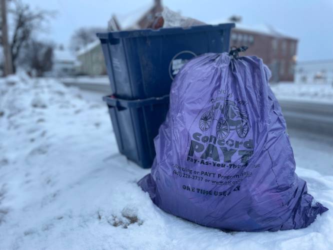 A “pay-as-you-throw” trash bag sits on the curb awaiting weekly pickup along with recycling in the city of Concord.