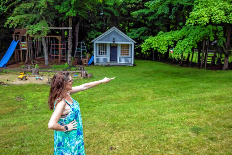 Robin Bach points to the woods in her backyard where two homeless camps are located on Wednesday, June 19, 2024. Her children do not play in the backyard because of the camps.