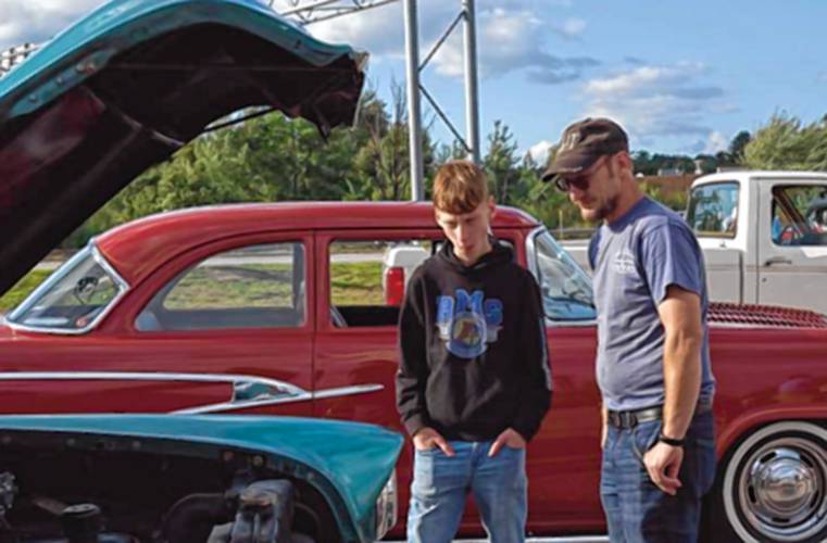 Lucas Durphey, 14, left, and his father Shannen Durphey look at a car’s engine at Classic Car Cruise Night in the parking lot of the Tilt’n Diner in Tilton on Thursday evening.