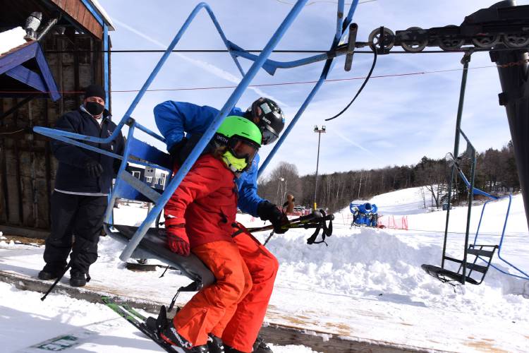 A Whaleback Mountain ski instructor helps a young skier onto the chairlift on Saturday, Feb. 13, 2021, in Enfield, N.H. 