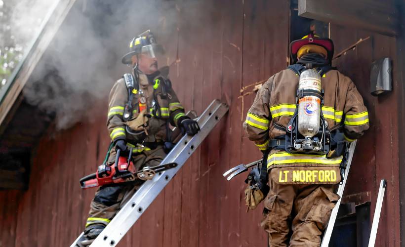 Firefighters vent the roof of the Carter Lodge at the Hidden Valley Scout Camp in Gilmanton on Monday. The fire at the camp went to two alarms and drew fire companies from the region.