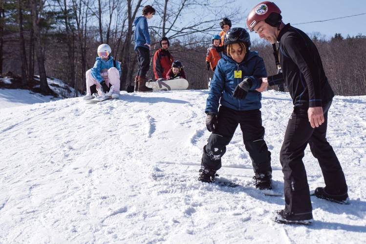Jhi Lucio, 8, left, receives a snowboarding lesson from instructor Adam Heath at the Veterans Memorial Ski Area in Franklin on Sunday afternoon. Heath is the assistant football coach at Franklin Middle School and gives his time at The Vets due to both love of snowboarding and the ski area. He has also enlisted several of his football players who snowboard to help teach.