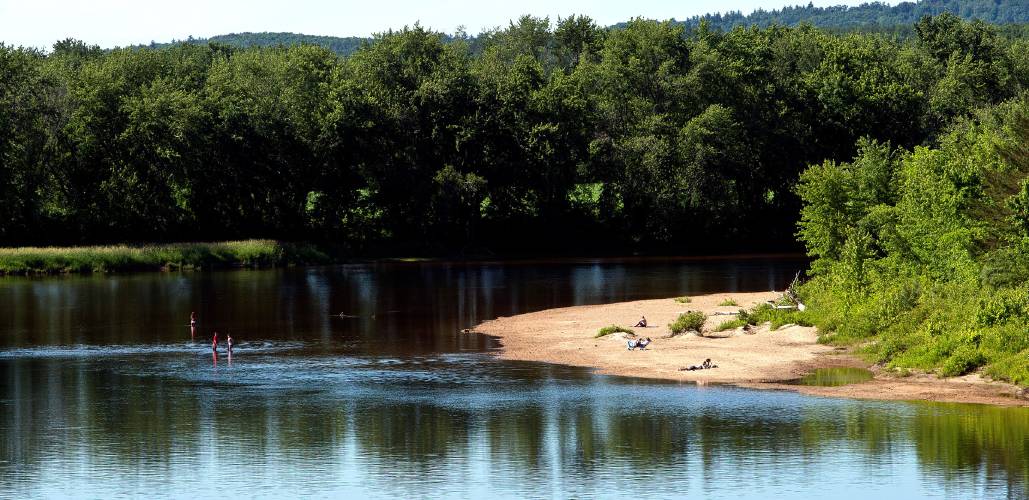 Sunbathers and swimmers enjoy the Merrimack River.