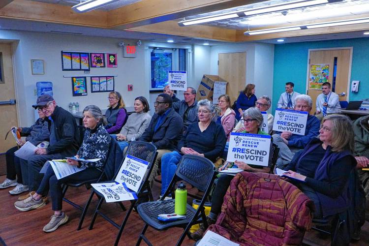 At a school district budget hearing, members of the Concord Concerned Citizens group held up signs asking the Concore School Board to reopen debate about where to put a new middle school. The board voted 6-3 in December to design a school relocated to current forest land near Broken Ground School.