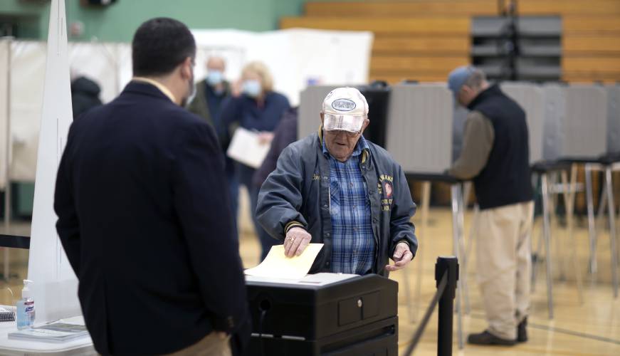 Louis Corson places his ballot in the electronic voting tally machine in the Hopkinton gym voting area on Tuesday, March 8, 2022.