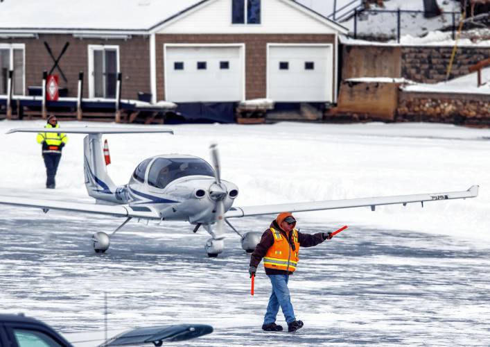 An aircraft official directs a plane on the ice at the Alton Bay airstrip on Sunday. The strip operates like any airport lacking a control tower. The ice on Lake Winnipesaukee must be at least a foot thick over a large area for landings.