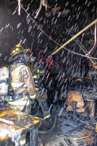 Firefighters spray water on the interior of the Carter Lodge at the Hidden Valley Scout Camp in Gilmanton on Monday, December 11, 2023. The smoky fire at the isolated camp drew two alarms and fire companies from around the area.
