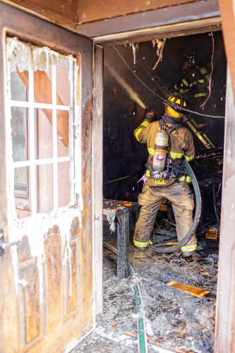 Firefighters spray water on the interior of the Carter Lodge at the  Hidden Valley Scout Camp in Gilmanton Monday. 