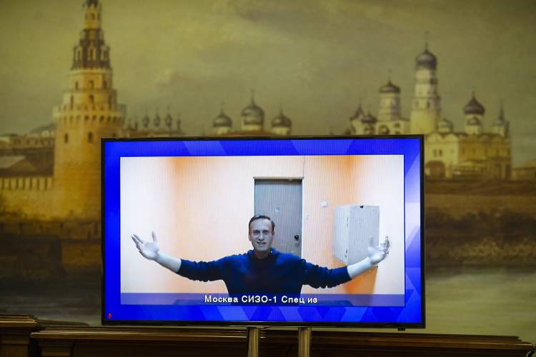 FILE - Russian opposition leader Alexei Navalny appears on a TV screen during a live session with the court during a hearing of his appeal in a court in Moscow, Russia, on Jan. 28, 2021 with a mural of the Moscow Kremlin in the background. Alexei Navalny, the fiercest foe of Russian President Vladimir Putin who crusaded against official corruption and staged massive anti-Kremlin protests, died in prison Friday Feb. 16, 2024 Russia’s prison agency said. He was 47. (AP...