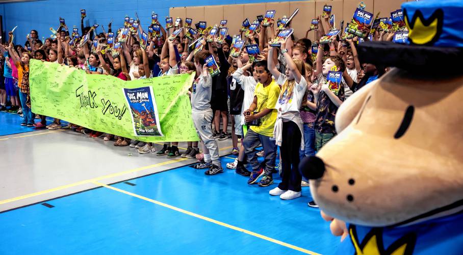 Students from the 2nd to 5th grade hold up Dav Pilkey’s latest book, “Dog Man: the Scarlet Shedder” as they get their photo taken at Beaver Meadow School on Monday.