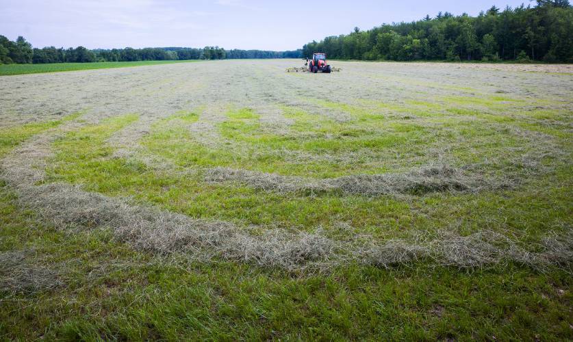 Rob Morrill has named his Kubota tractor 'The Orange Stepson,' as he climbs aboard it to work on gathering hay on a leased field in Concord.