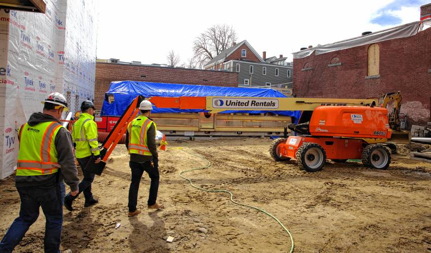 The construction of the Friendly Toast and Arts Alley in downtown Concord is taking shape. Construction workers walk through the back alley of the project with the wrapped-up diner in the background.