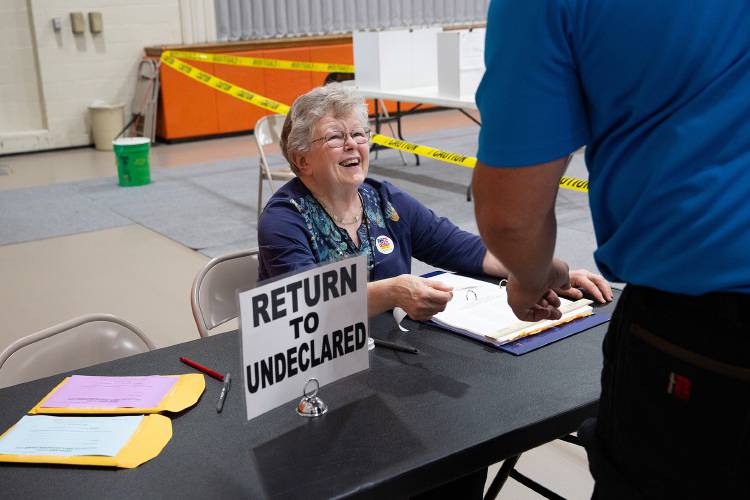 Pris Hagebusch helps voters return to undeclared status after voting in primary elections at Newport Middle High School in Newport, N.H., on Tuesday, Sept. 13, 2022.