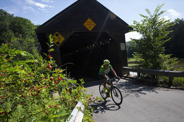 A biker rides over the Edgell Covered Bridge while participating in the Prouty Ultimate in Lyme, N.H., on Friday, July 14, 2023. (Valley News / Report For America - Alex Driehaus) Copyright Valley News. May not be reprinted or used online without permission. Send requests to permission@vnews.com.