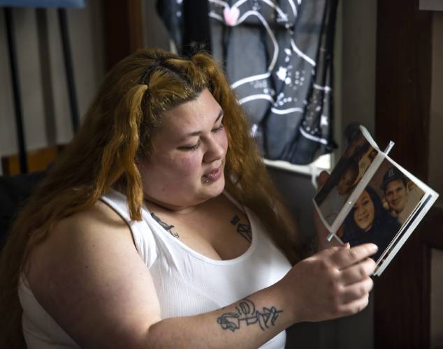 Brie Lamarche looks at a photo of  her with her father. The photographs help her connect back to memories of her childhood, including this photo of her in a graduation cap and gown.