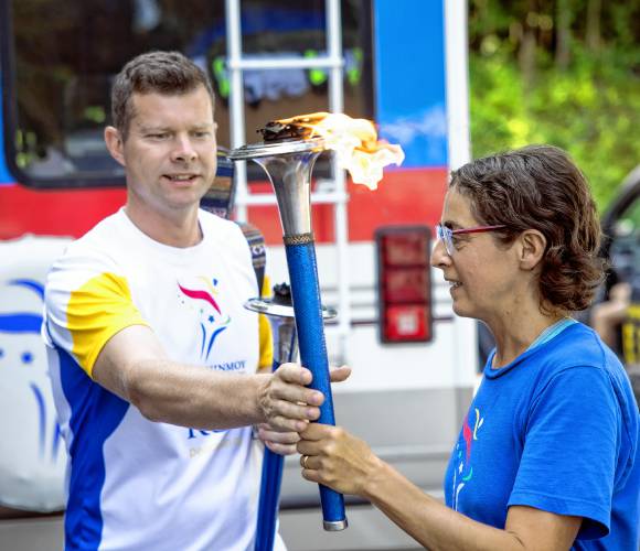 Edgars Ancans of Latvia and Nayaja Perugini of Italy exchange torches before greeting the children at the Boys and Girls Club in Concord on Tuesday, August 13, 2024, before heading to Boston on their peace run.
