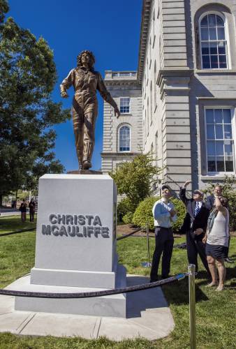 Steven McAuliffe, center, shields his eyes as he looks up at the statue along with his daughter, Caroline, as sculptor Benjamin Victor, left, and Gov. Chris Sununu look on at the unveiling of the statue of Christa McAuliffe at the dedication on the State House grounds on Monday.