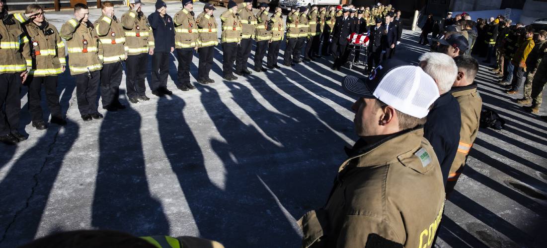 Firefighters from around the region salute as a color guard brings out Christopher Girard from the Medical Examimer’s office at Concord Hospital on Monday. Girard died unexpectedly Saturday after a brief illness. 
