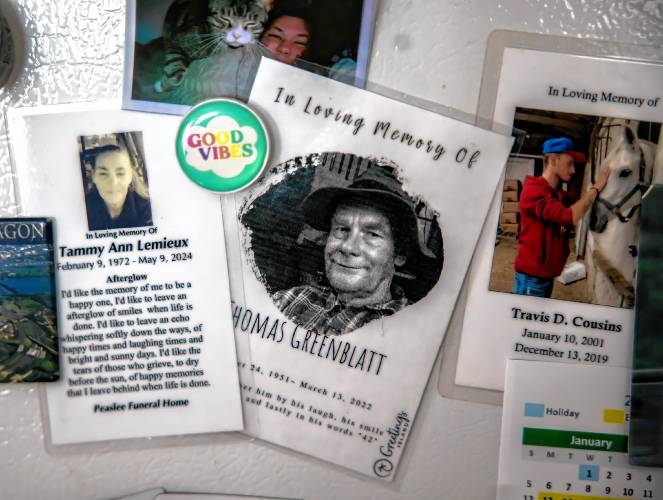 Memorial cards of people hang on Brie’s refrigerator.